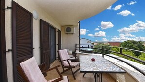 A balcony with two wooden chairs, a table, and a red cup. - Charming apartment with balcony and pool (Peroj)