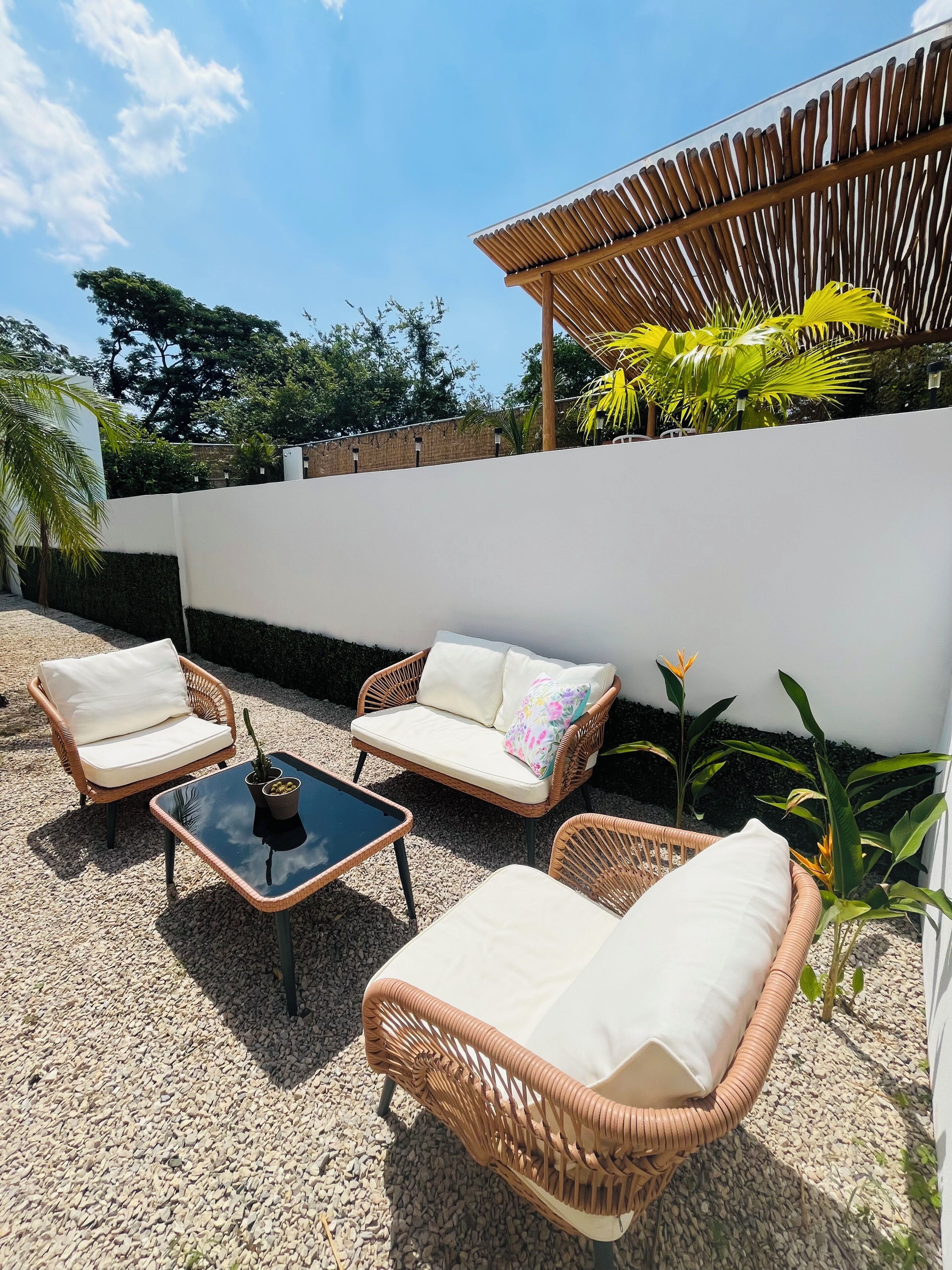 Un patio con mobiliario de mimbre, una mesa y una pérgola.