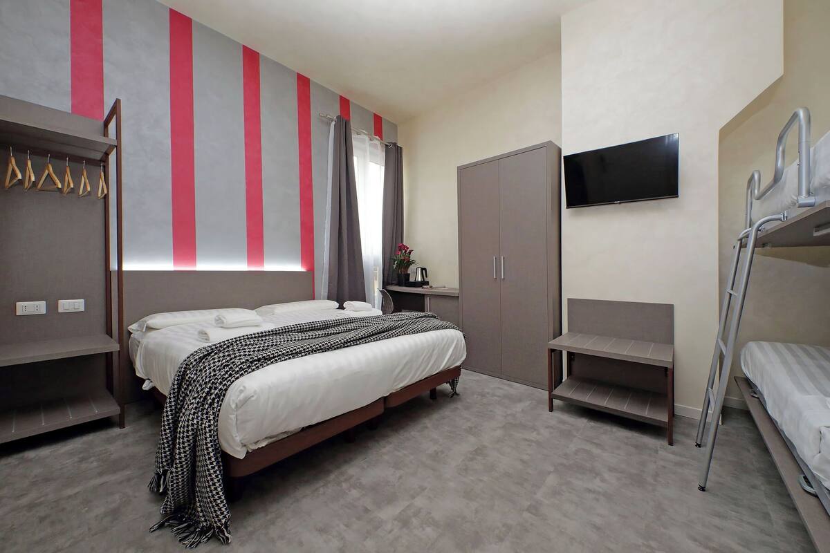 A bedroom with a bed, a wardrobe, a TV, and a bunk bed.