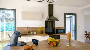 Una cucina moderna con una macchina per il caffè, una ciotola di frutta e una bottiglia di succo d'arancia sul bancone.