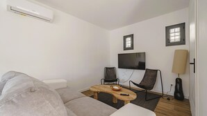 Un soggiorno moderno con un divano, un tavolino, una televisione e una finestra.