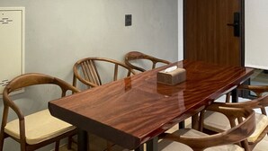 A conference room with a long wooden table, six chairs, a white air conditioning unit, and a wooden door. - Wu Sheng Stay (Tainan)