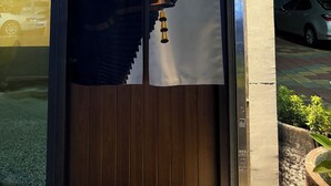 A traditional Japanese building entrance with a wooden door and a large paper with Chinese characters. - Wu Sheng Stay (Tainan)