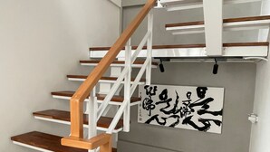 A staircase with wooden steps and white railings, leading to a landing with a wall-mounted artwork. - Wu Sheng Stay (Tainan)