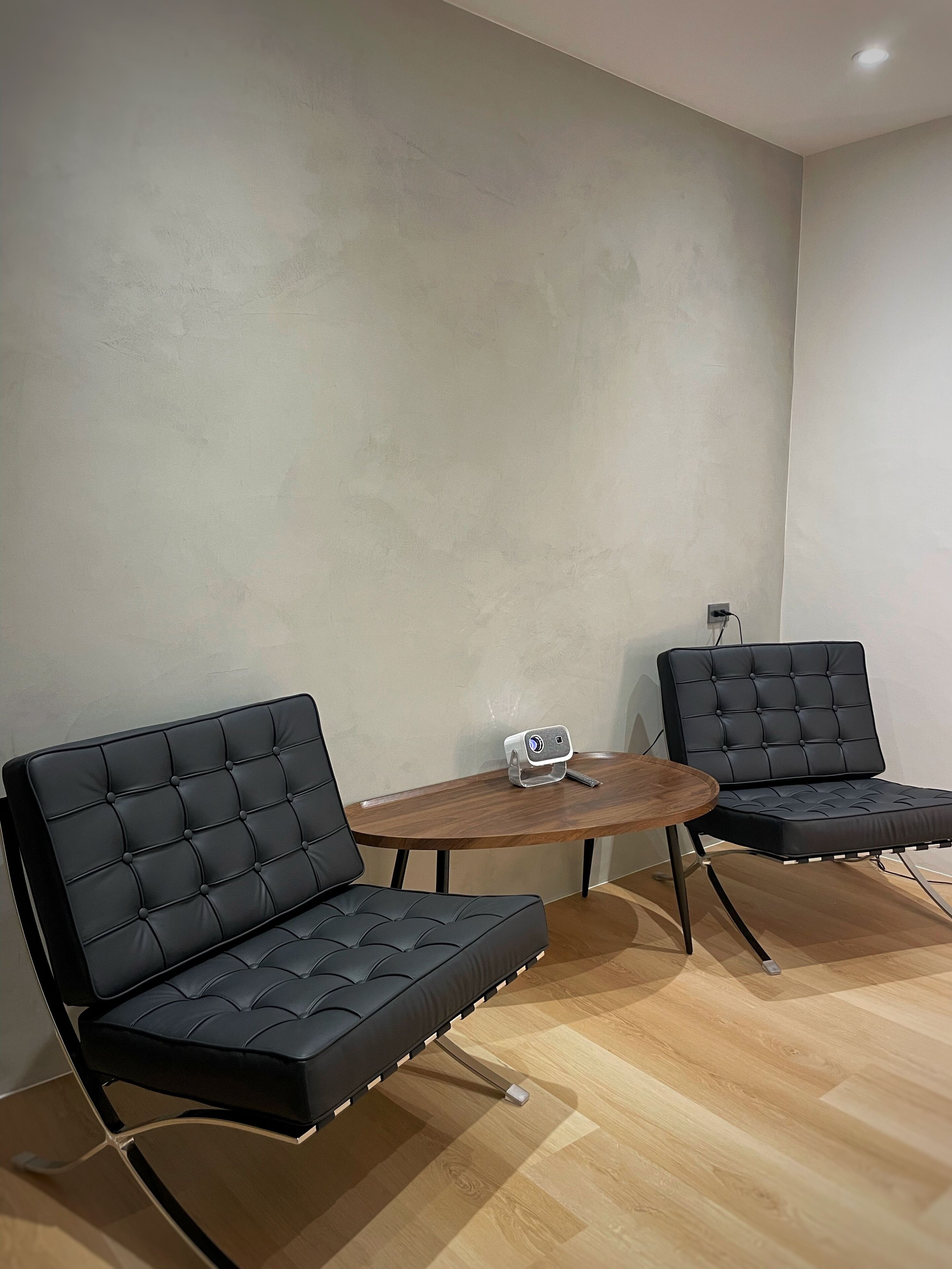 Une pièce moderne avec deux canapés en cuir noir et une petite table en bois.