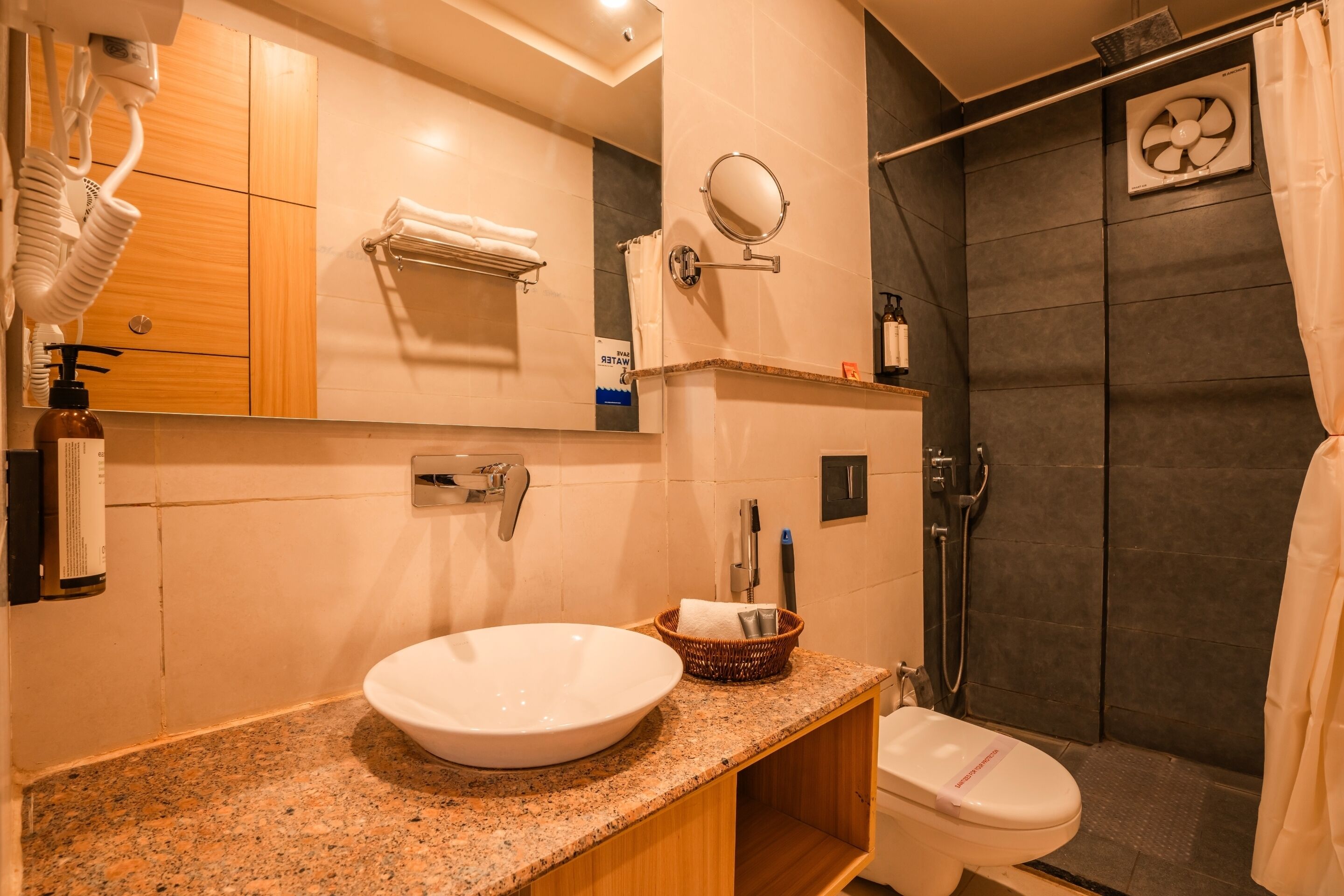 A modern bathroom with a granite countertop, a white sink, a toilet, a shower with a glass door, and a towel rack.