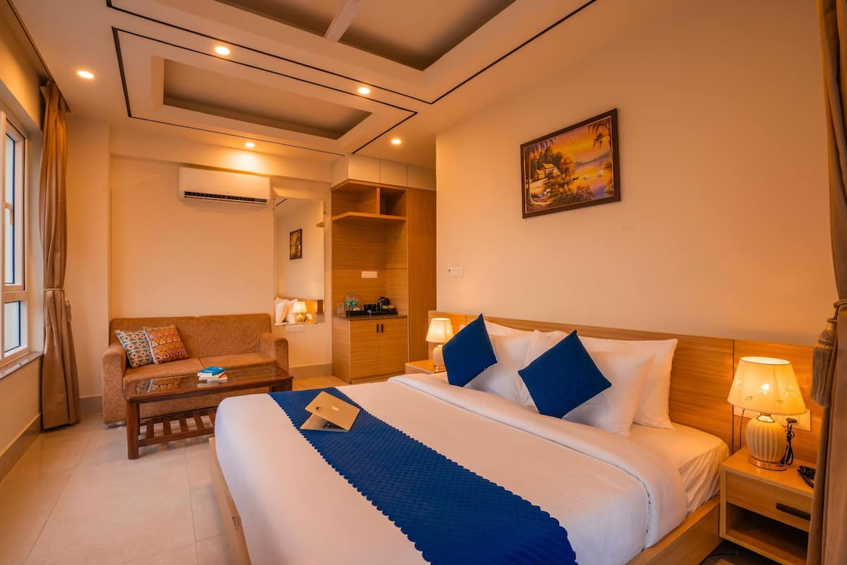 Habitación de hotel con una cama grande, un sofá, un escritorio y un cuadro en la pared.