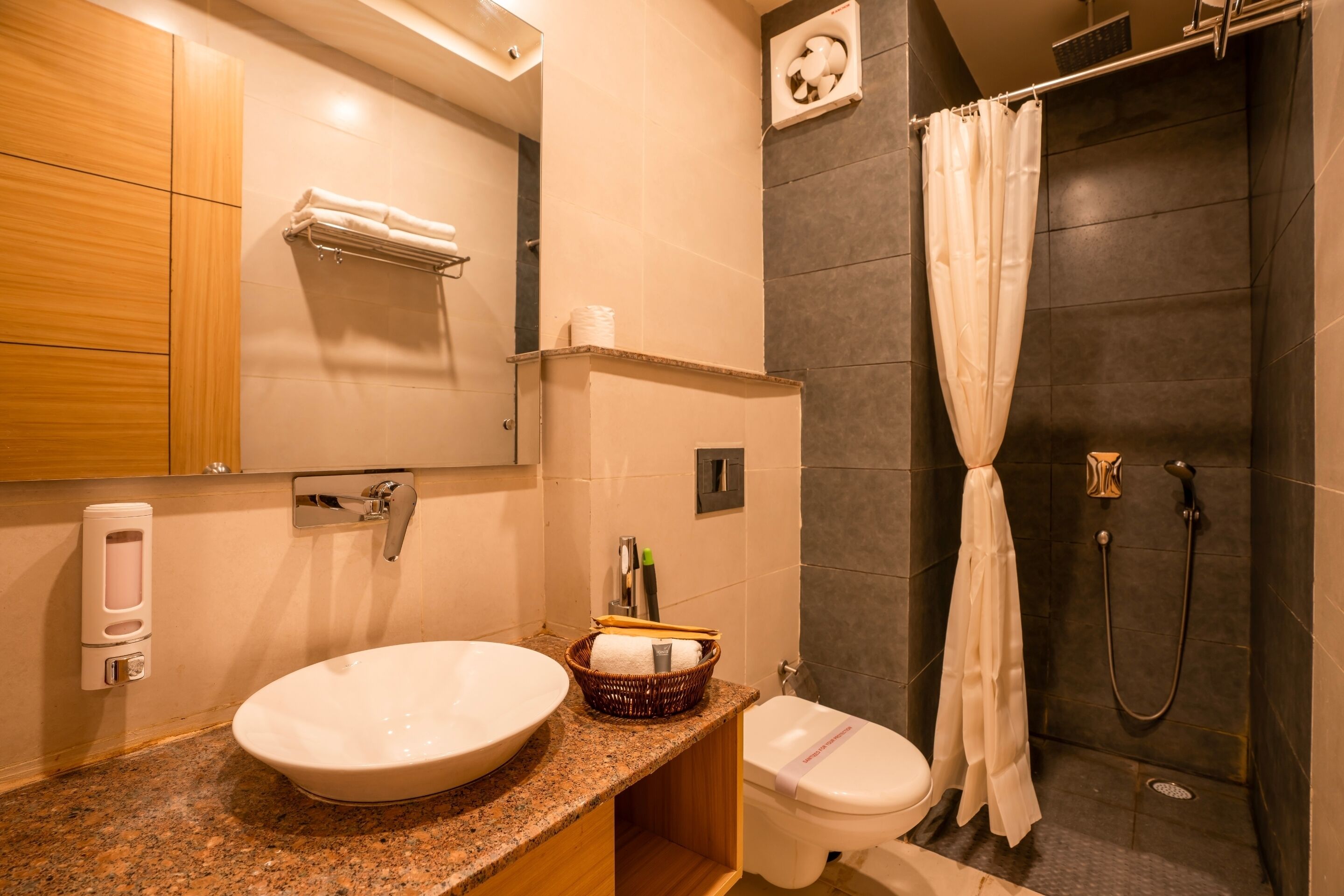 Un bagno moderno con un piano di lavoro in granito, un lavandino bianco, un water e una doccia con tenda.