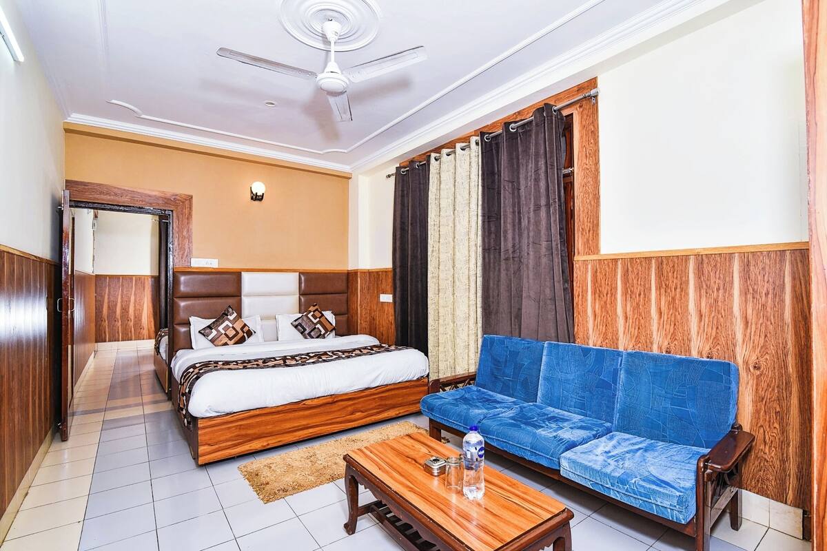 Une chambre d’hôtel avec un lit, un canapé, une table basse en bois et un ventilateur de plafond.