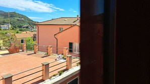 A view of a building with a red facade, a tiled roof, and a balcony with a metal railing. - Appartamento Trigoso (Sestri Levante)