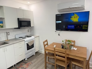 A modern kitchen with white cabinetry, a microwave, stove, and a Samsung TV displaying a cartoon character.