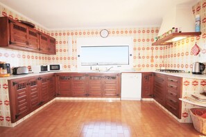 Kitchen features a central island with a sink and microwave, wooden cabinets, and a clock on the wall.