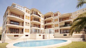 Un immeuble résidentiel à plusieurs étages, doté de balcons, d’une piscine et d’une pelouse bien entretenue.