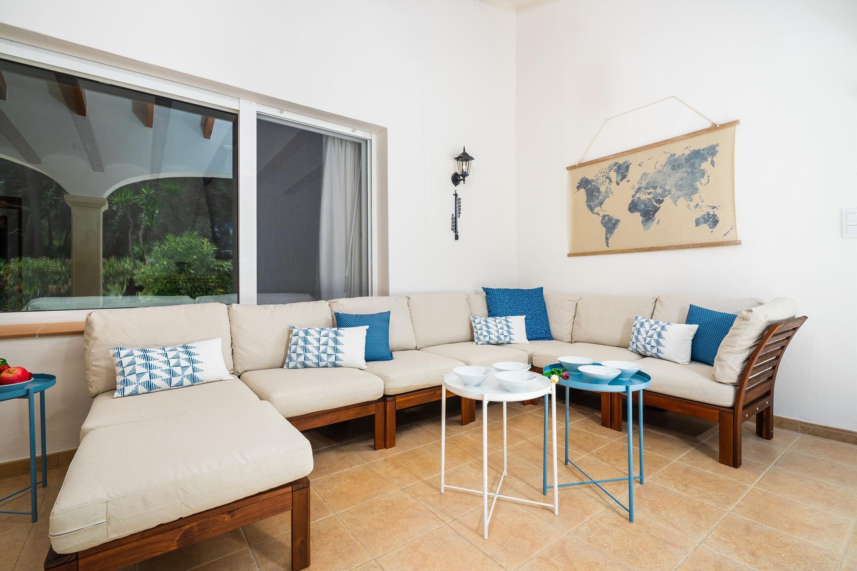 Un salon moderne avec un canapé d’angle beige, une petite table ronde et une carte du monde accrochée au mur.