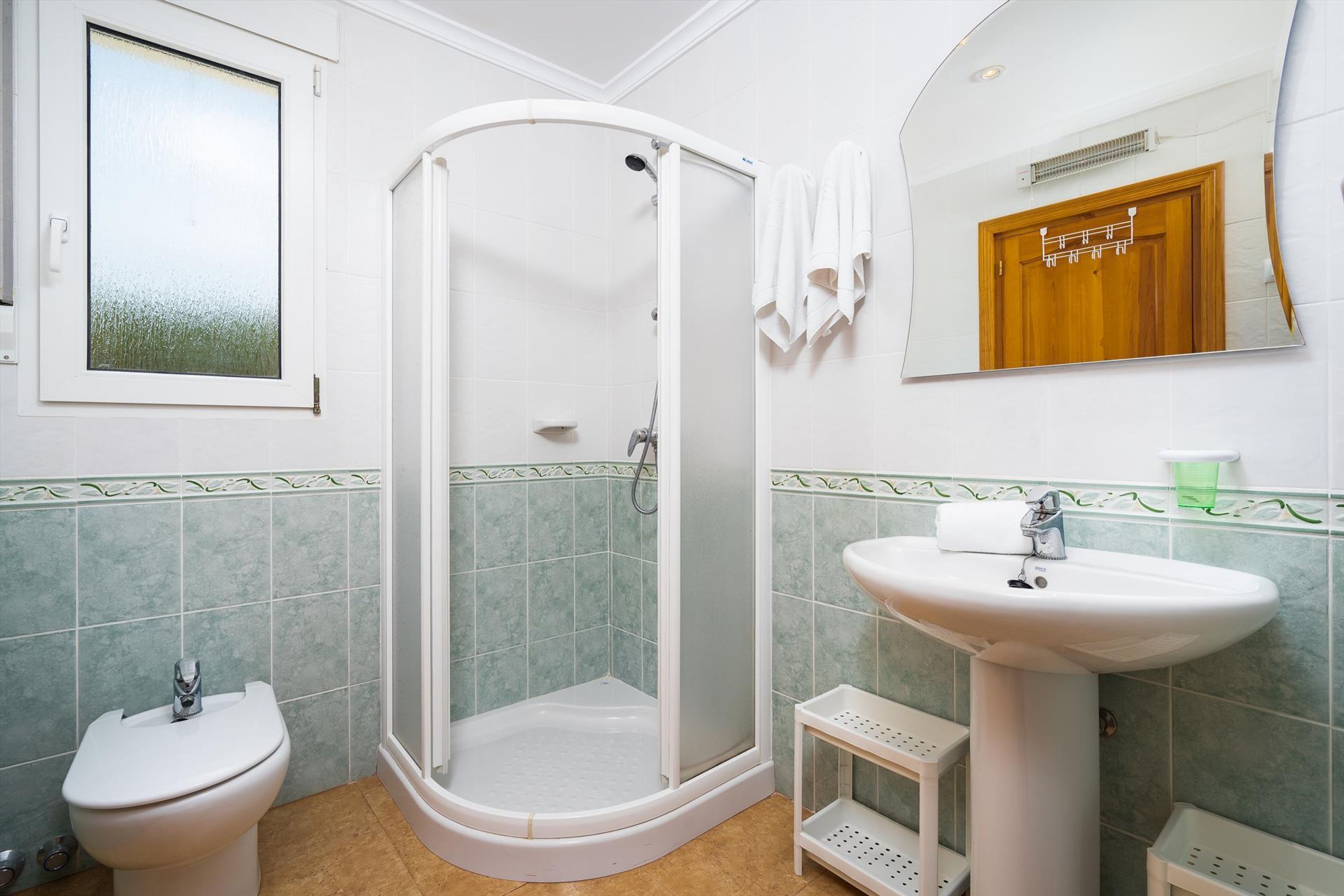 Une salle de bain équipée d’une douche, de toilettes, d’un lavabo et d’un miroir.