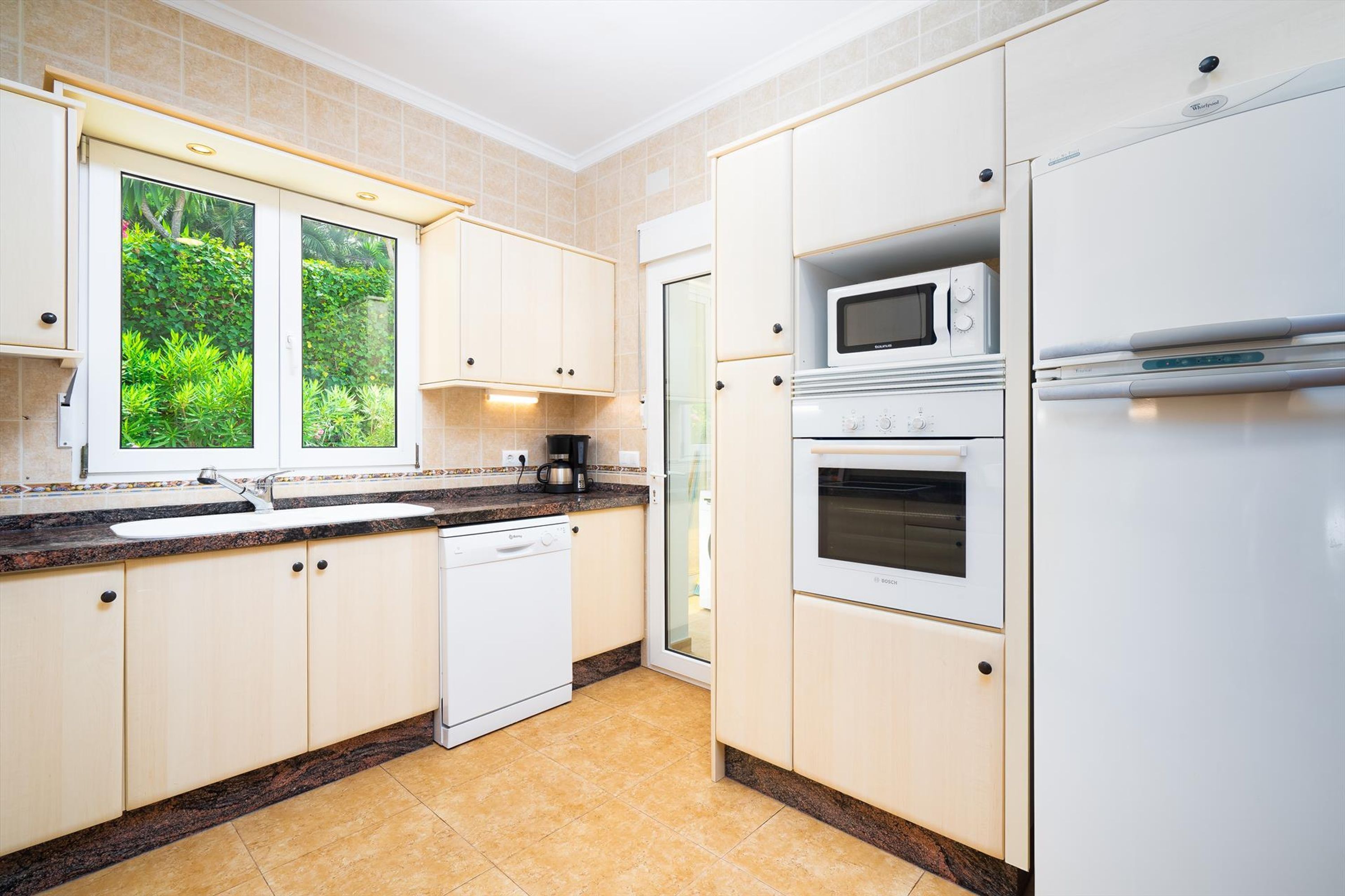 A modern kitchen with white cabinets, a built-in microwave, oven, and dishwasher.