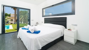 A modern hotel room with a large bed, a nightstand, and a view of a swimming pool. - Villa Vera in Javea With 4 Bedrooms and 2 Bathrooms (Javea)