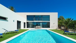 A modern house with a swimming pool, a patio with chairs, and a clear blue sky. - Villa Vera in Javea With 4 Bedrooms and 2 Bathrooms (Javea)