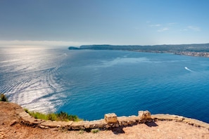 A coastal view with a stone wall in the foreground and a clear blue sea extending to the horizon. - Golden in Javea With 3 Bedrooms and 2 Bathrooms (Javea)