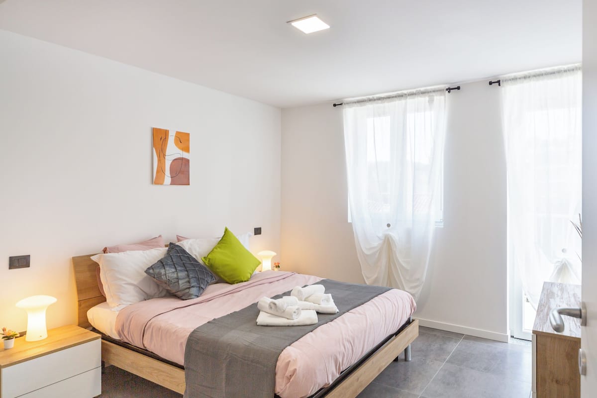A modern bedroom with a bed, bedside tables, and a window with curtains.