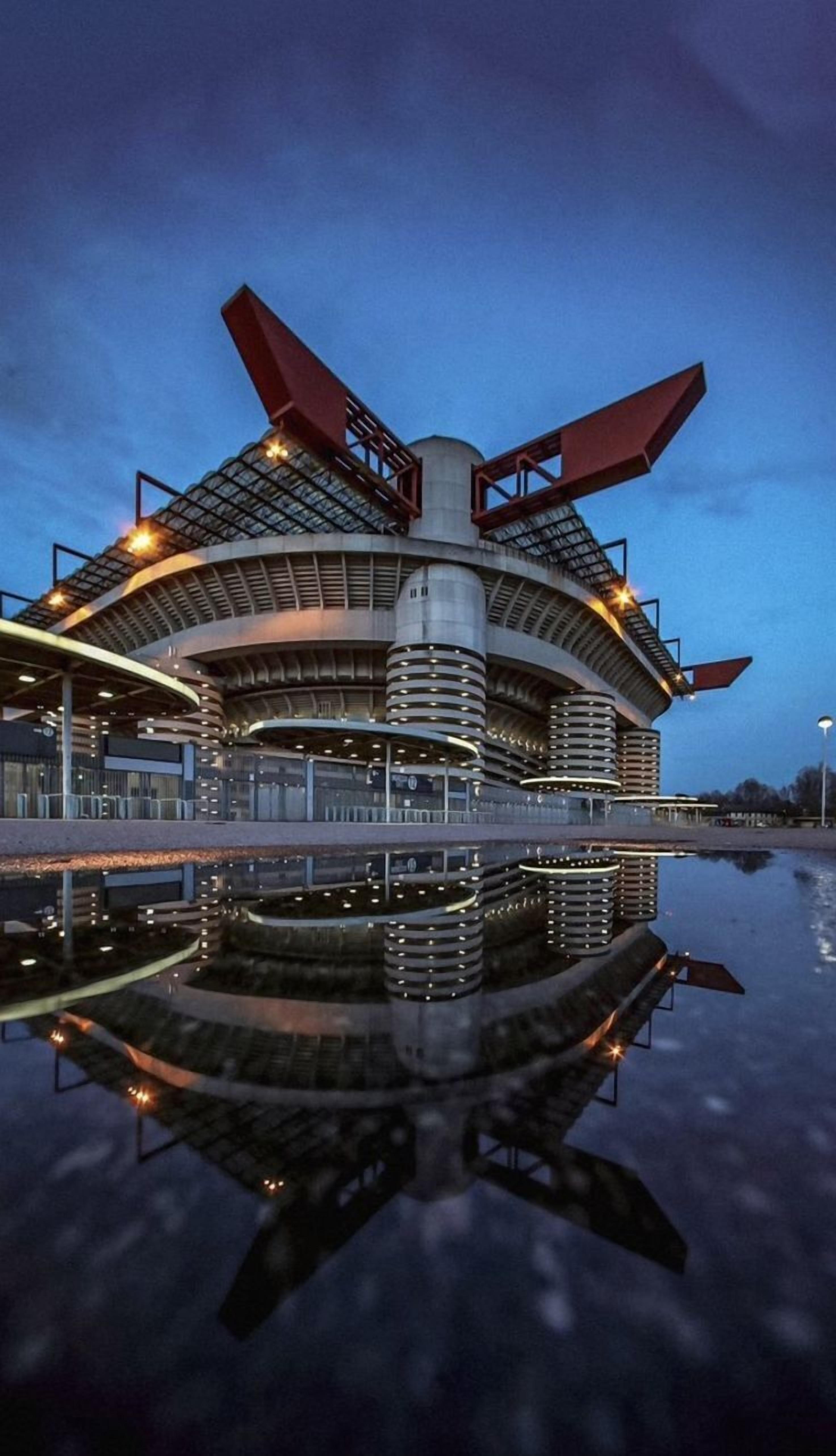 A modern building with a circular design, featuring a central cylindrical tower and multiple levels with balconies.