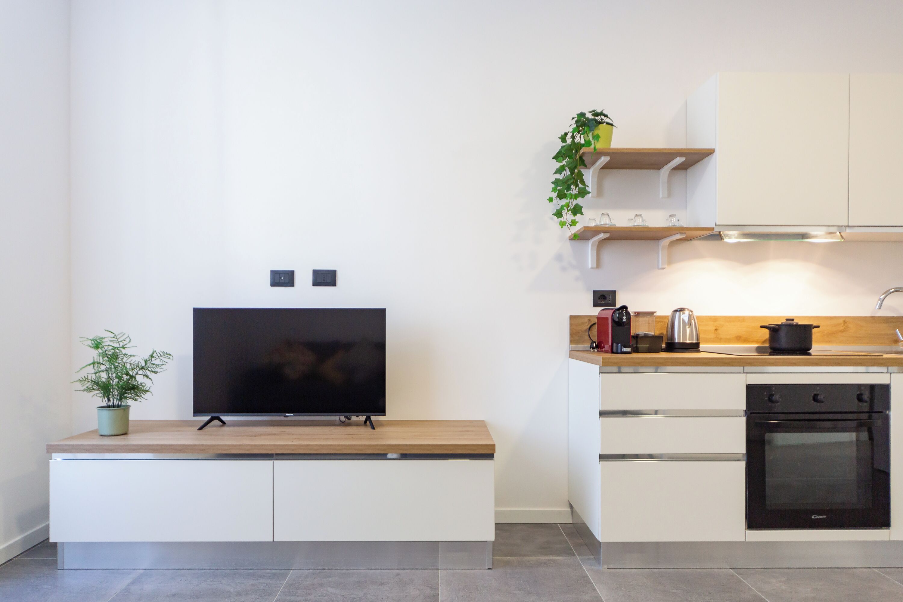 Eine moderne Küche mit integriertem Fernseher, einer Holz Arbeitsplatte und Edelstahlgeräten.