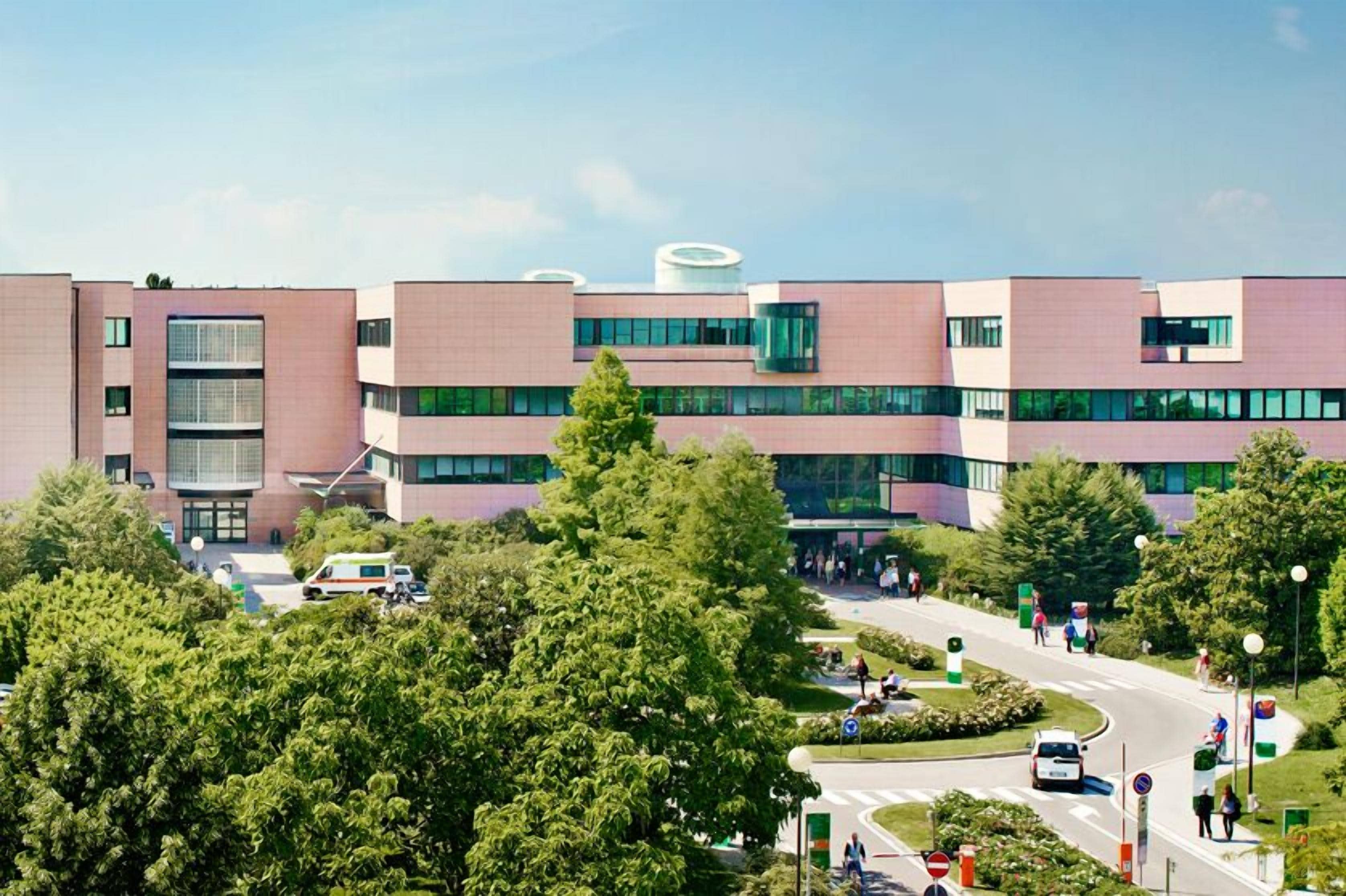 A modern building with multiple floors, large windows, and a central courtyard with greenery.