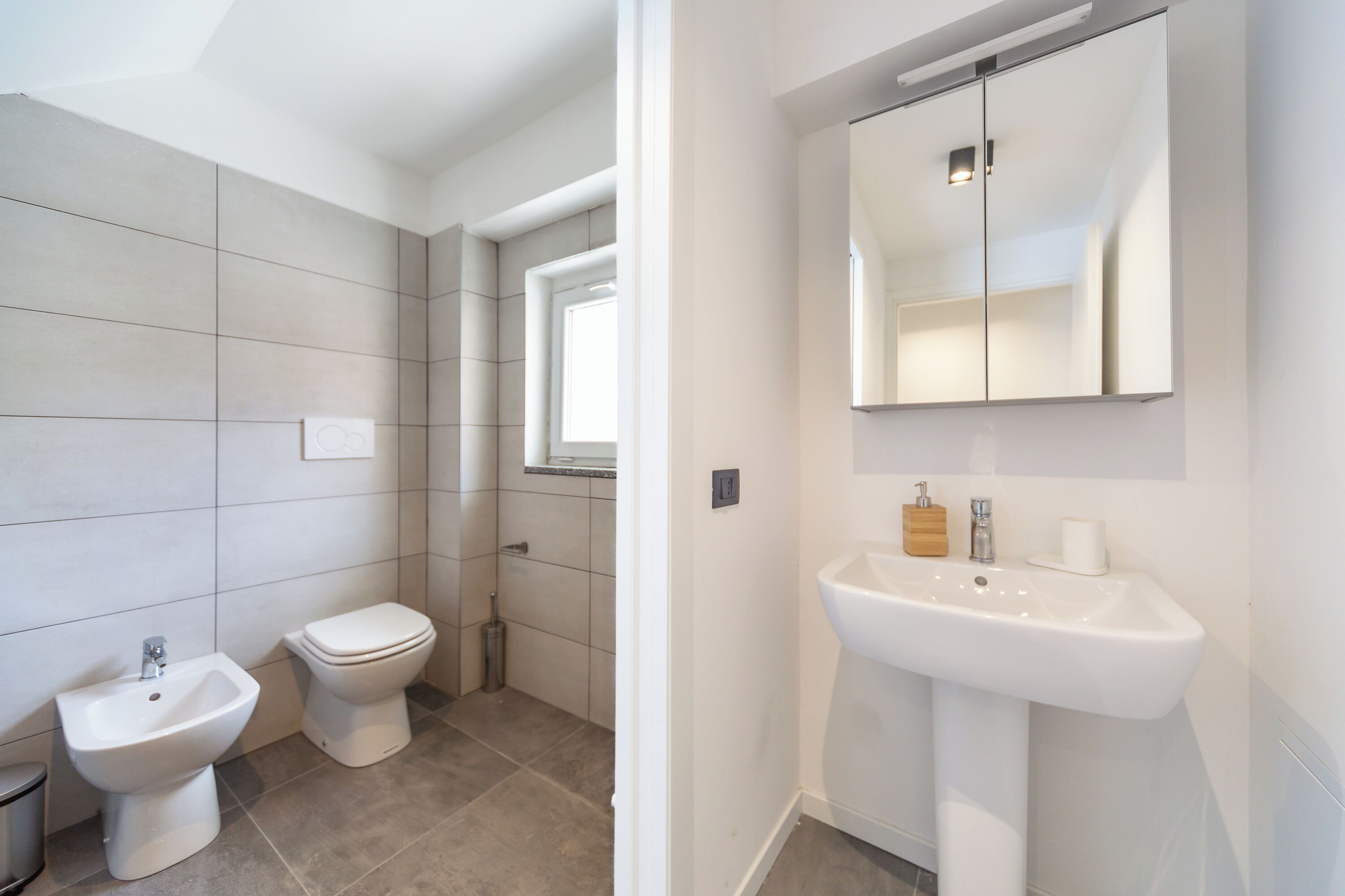 A modern bathroom with a bidet, toilet, and sink.