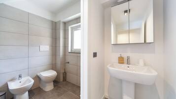 A modern bathroom with a bidet, toilet, and sink.
