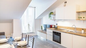 A modern kitchen with a skylight, built-in appliances, and a dining area with a table set for four. - KHL apartments (Milan)