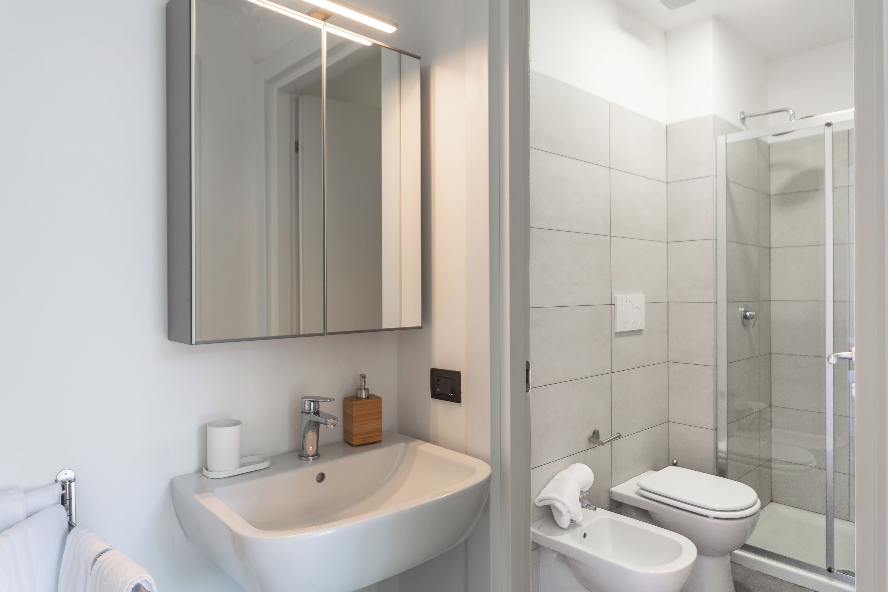 Een moderne badkamer met een grote spiegel, een wastafel, een toilet en een douchecabine.