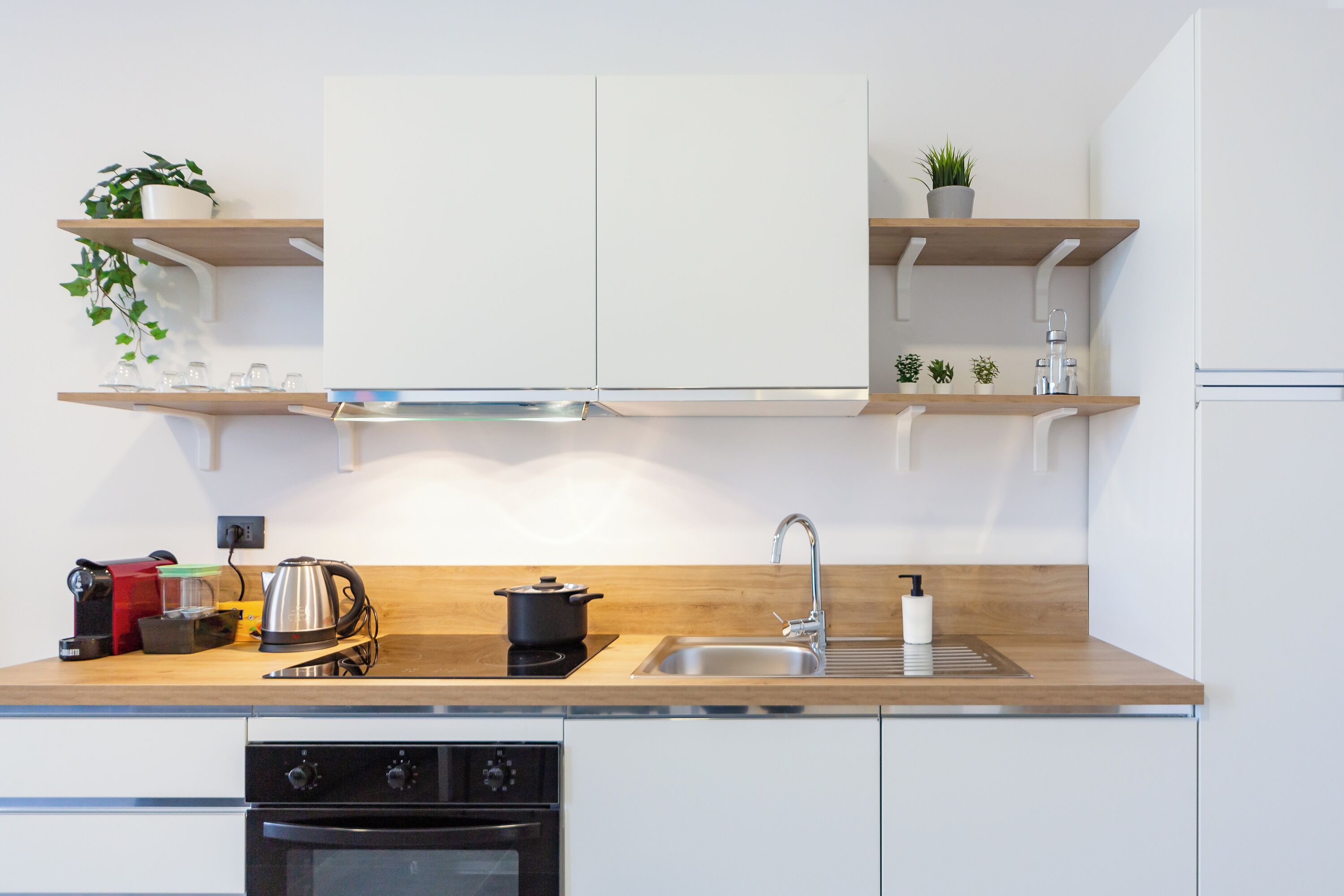 Eine moderne Küche mit weißen Schränken, Holz Arbeitsplatten und eingebauten Regalen mit Pflanzen.