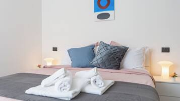 Ein ordentlich bezogenes Bett mit Kissen, einer Nachttischlampe und einem Wandbild.