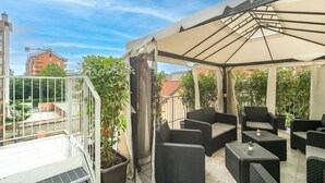 A covered outdoor seating area with wicker furniture and a large umbrella. - KHL apartments (Milan)