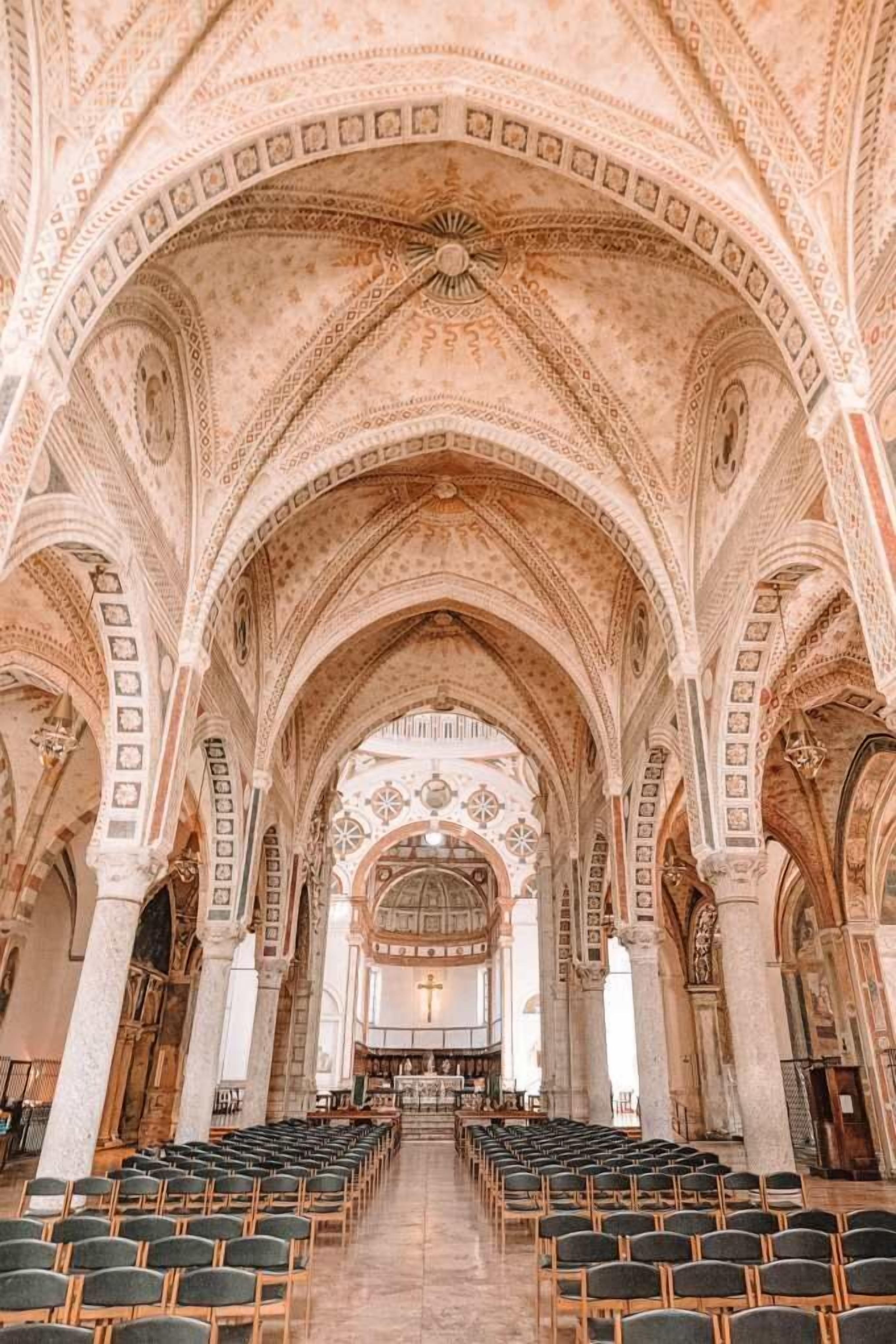 L’intérieur d’une église, avec de hauts plafonds en voûte, des rangées de bancs et un autel central.