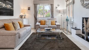 A modern living room with a beige sofa, a glass coffee table, and a fireplace. - Villa Eva in J vea With 3 Bedrooms and 2 Bathrooms (Javea)