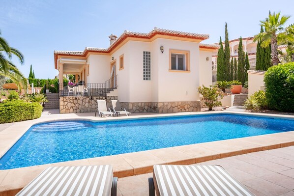 Une maison avec une piscine, des marches en pierre et une terrasse dotée de chaises longues.