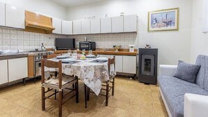 Une cuisine compacte avec des meubles blancs, une table à manger pour quatre personnes, une petite cuisinière et un four à micro-ondes encastré.