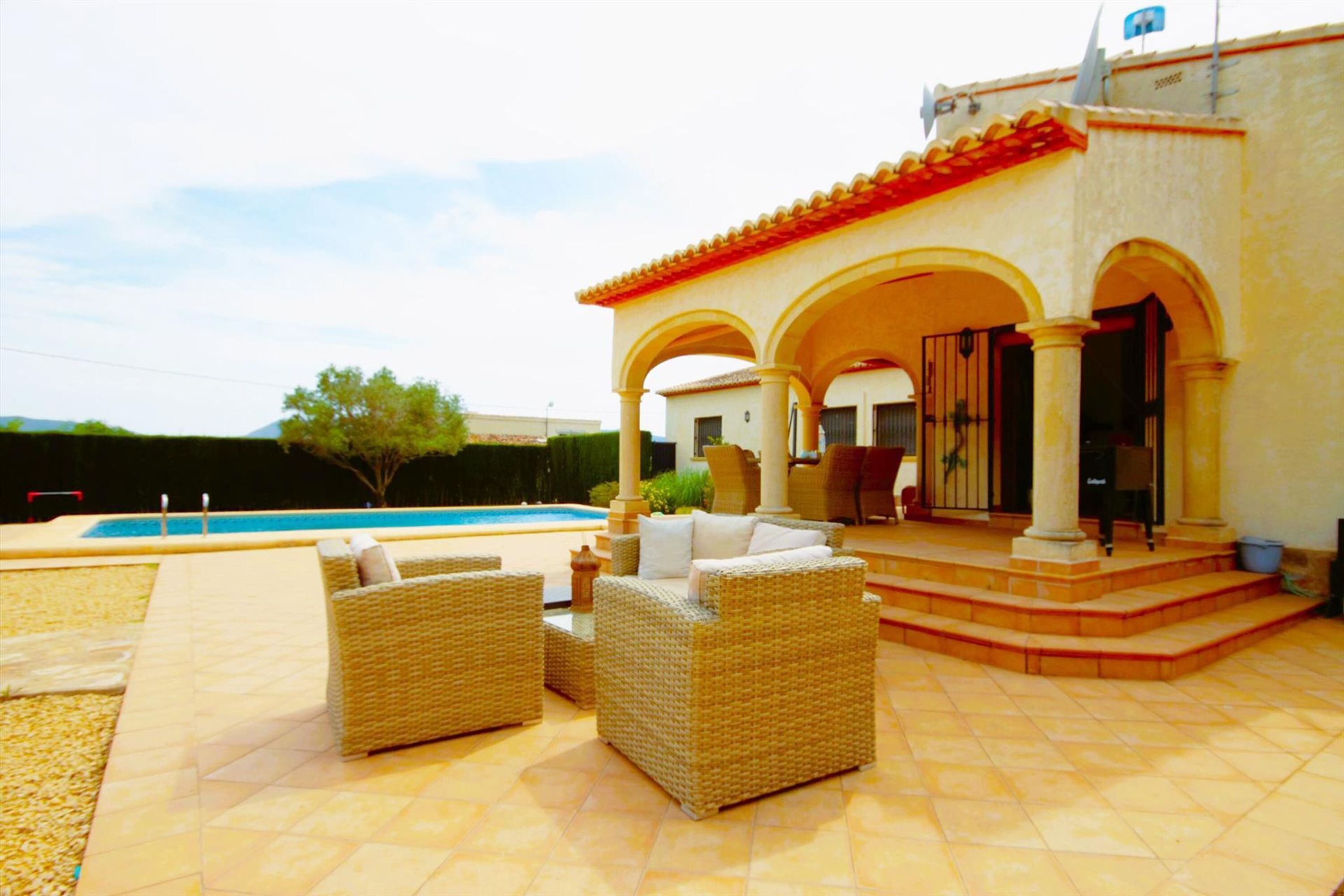 A house with a swimming pool, outdoor seating, and a covered patio area.