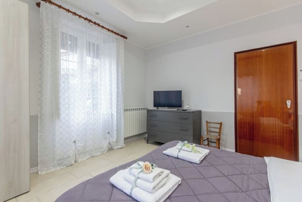 A bedroom with a bed, a dresser, a television, and a wooden door.