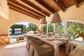 An outdoor dining area with wicker furniture, a wooden table, and hanging wicker lamps. - Calimero Alegria Sl in Son Caulelles (Marratxi)