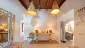 Een kamer met een houten bank, een tafel met twee lampen en een grote spiegel.