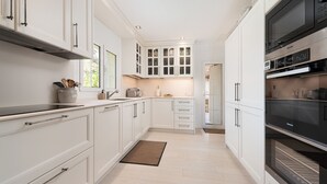 Een moderne keuken met witte kasten, roestvrijstalen apparatuur en een houten vloer.