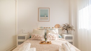A neatly made bed with towels, a tray with glasses and a bottle, and pillows with "Relax" text. - Modern Riviera Golf Y Mar (Mijas)