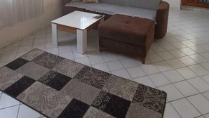A living room with a sofa, a coffee table, and a patterned rug. - Karya Konaklama (Antalya)