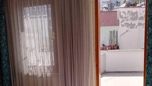 A room with a bed, a window with curtains, and a view of the outside. - Karya Konaklama (Antalya)