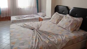 A hotel room with two beds, a ceiling fan, a painting, and a window with curtains. - Karya Konaklama (Antalya)