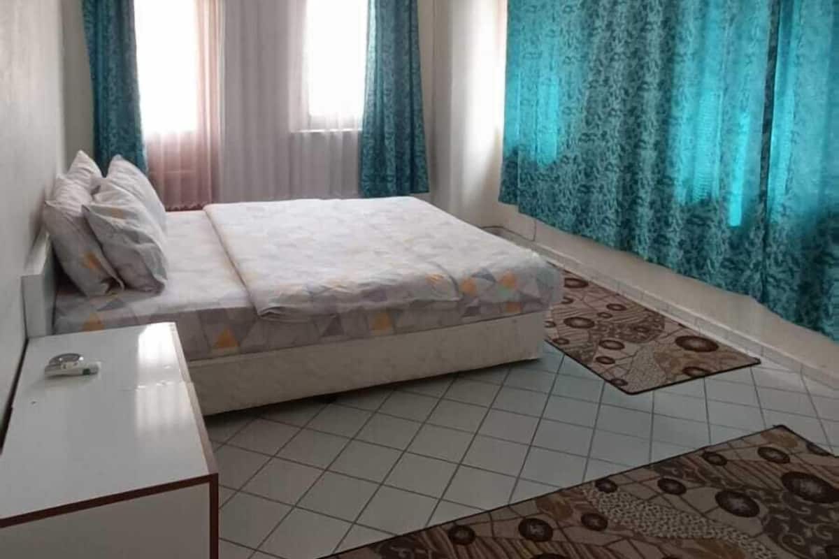 Un dormitorio con cama, escritorio y ventana con cortinas.