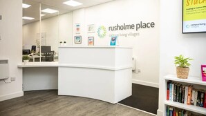 Una recepción con un cartel que dice "Rusholme Place campus living villages" y una estantería con libros.