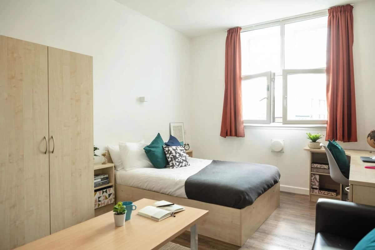 Une chambre à coucher au style minimaliste, avec un lit, un bureau et une armoire.